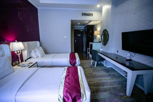 a hotel room with two beds and a desk at Sutanraja Hotel & Convention Centre in Soreang