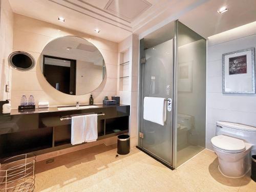 a bathroom with a toilet and a sink and a mirror at Swiss Grand Xiamen-Harbour View in Xiamen