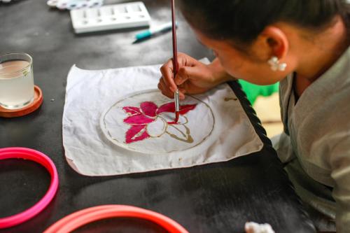 a man is painting a plate on a table at Darmada Eco Resort in Sidemen
