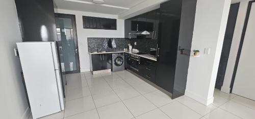a kitchen with black cabinets and a washing machine at 247 Luxury Stays in Windhoek