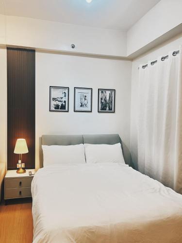 a bedroom with a large white bed and three pictures on the wall at The Stars Lil' Suite in Trece Martires