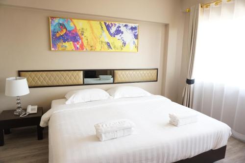 a large white bed with two white towels on it at Taris Art Hotel Phrae in Phrae