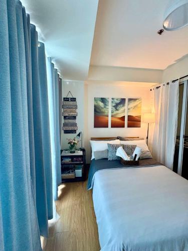 une chambre avec un grand lit avec des rideaux bleus dans l'établissement Bahay-Bahayan, à Manille