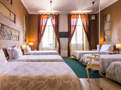 ポルトにあるペドラ イベリカのベッド4台と窓2つが備わるホテルルームです。