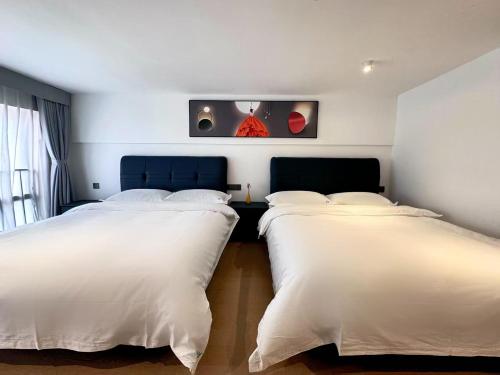 two beds in a room with white sheets at Mihua International Apartment - Guangzhou Yangang Subway Station Branch in Guangzhou