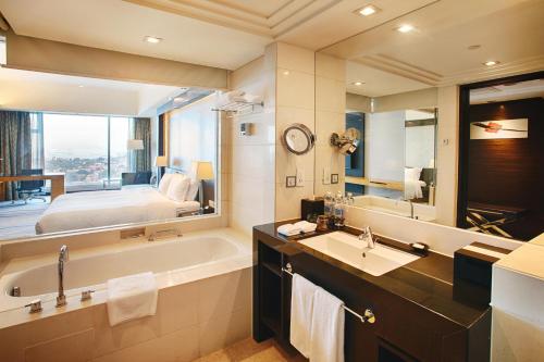 a bathroom with a tub and a bed and a sink at Swiss Grand Xiamen-Harbour View in Xiamen