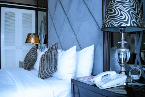 a bedroom with a bed with a phone and a lamp at Sutanraja Hotel & Convention Centre in Soreang