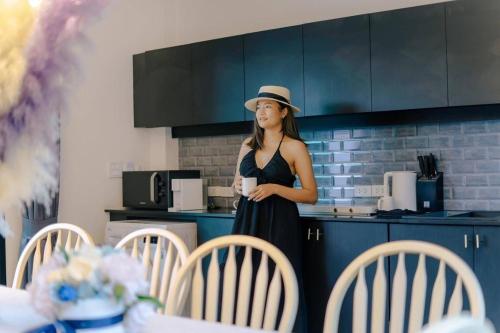 a woman standing in a kitchen holding a cup of coffee at Hua Hin Pool Villa and Pool table with 3 bedrooms, 3 bathrooms near Cha-Am beach in Nikhom Sang Ton Eng Khuan Phet