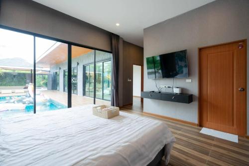 a bedroom with a large bed and a tv on the wall at Hua Hin Pool Villa and Pool table with 3 bedrooms, 3 bathrooms near Cha-Am beach in Nikhom Sang Ton Eng Khuan Phet
