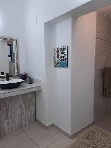 a bathroom with a sink and a mirror at Beach Walk Cottage in Plettenberg Bay