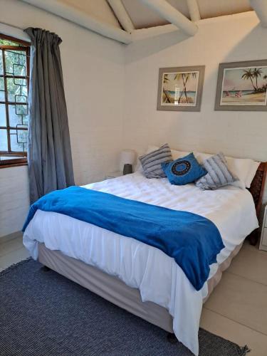 a bedroom with a large bed with a blue blanket at Beach Walk Cottage in Plettenberg Bay
