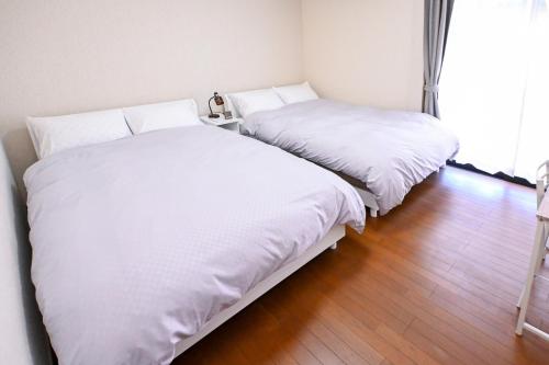 two beds in a room with white sheets at Bhome Hikone Jizo in Hikone
