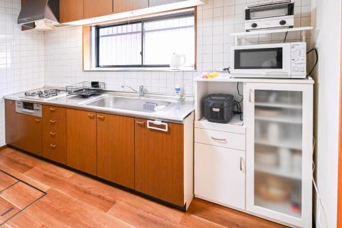a small kitchen with a sink and a microwave at Bhome Hikone Jizo in Hikone