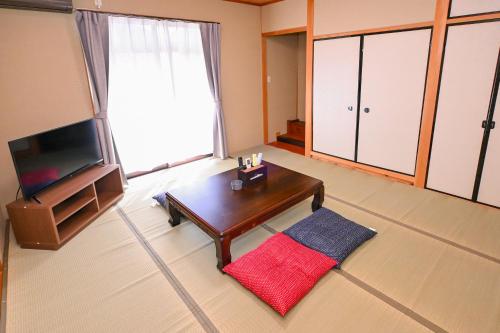 a living room with a tv and a coffee table at Bhome Hikone Jizo in Hikone