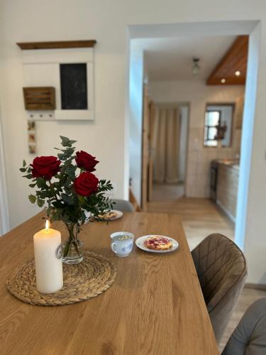 a table with a vase of roses and a candle at Horský domek se zahradou na Javorné u Železné Rudy in Čachrov