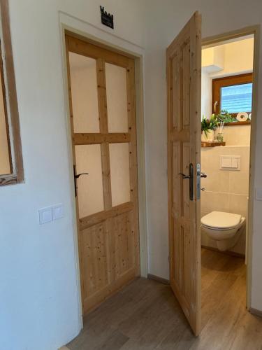 a bathroom with a toilet and a wooden door at Horský domek se zahradou na Javorné u Železné Rudy in Čachrov