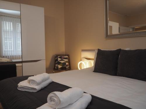 a bedroom with towels on a bed with a mirror at Grand-Tourist Posejdon Apartments in Gdańsk