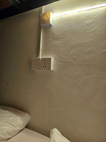 a room with a bed and a light on the wall at AeCOTEL Mingle Hostel in Sandakan