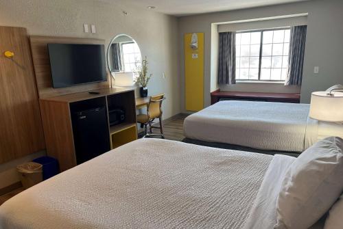 a hotel room with two beds and a flat screen tv at Days Inn by Wyndham near Kansas Speedway in Kansas City