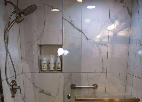 una doccia con porta in vetro e 2 bottiglie di Ramada Plaza by Wyndham Garden Grove/Anaheim South ad Anaheim