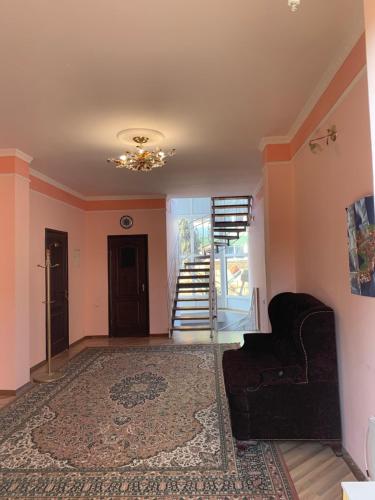 a living room with a black couch and a staircase at Гостевой дом "Светлана" in Cholpon-Ata