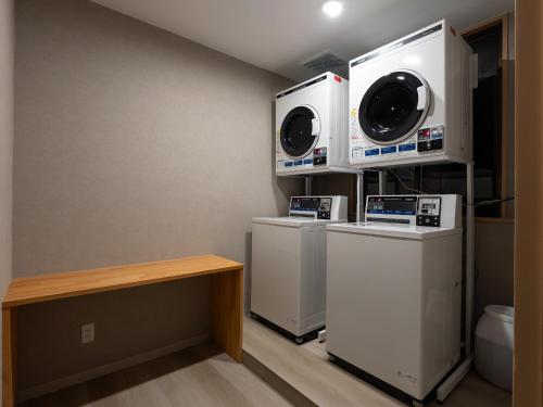 a laundry room with two washer and dryers at Ryokan Gizan in Takayama