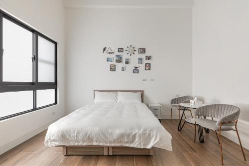 a white bedroom with a bed and a chair at Xiao San Chill in Xiaoliuqiu