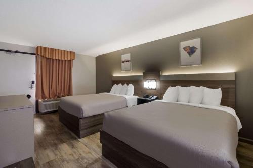 a hotel room with two beds and a window at Quality Inn Fort Jackson in Columbia