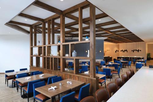 a dining room with wooden tables and blue chairs at Doubletree By Hilton Battle Creek in Battle Creek
