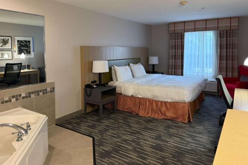 a hotel room with a bed and a bath tub at Country Inn & Suites by Radisson, Elgin, IL in Elgin