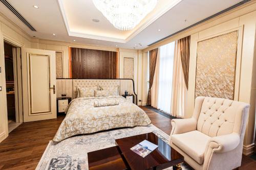 a bedroom with a bed and a chair and a chandelier at Hilton Garden Inn Samarkand Sogd in Samarkand