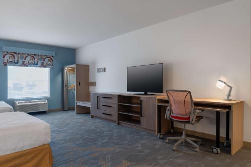 a hotel room with a desk with a computer and a television at Home2 Suites By Hilton Troy, Al in Troy