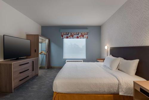 a hotel room with a bed and a flat screen tv at Home2 Suites By Hilton Troy, Al in Troy