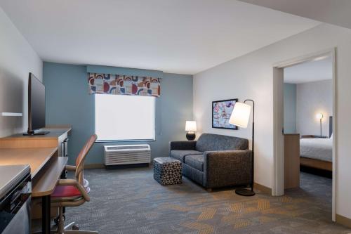 a hotel room with a couch chair and a projection screen at Home2 Suites By Hilton Troy, Al in Troy