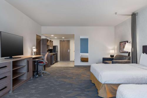 a hotel room with two beds and a desk with a television at Home2 Suites By Hilton Troy, Al in Troy
