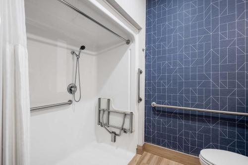 a blue tiled bathroom with a toilet and a shower at Spark by Hilton Dumas in Dumas