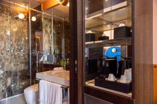a bathroom with a sink and a toilet and a mirror at Cenica Porto Hotel, Curio Collection By Hilton in Porto