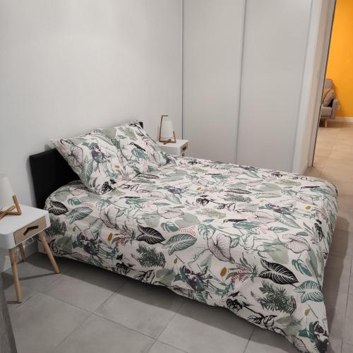- une chambre avec un lit doté d'un couvre-lit fleuri dans l'établissement Appartement Cosy avec place de parking privée, au Mans