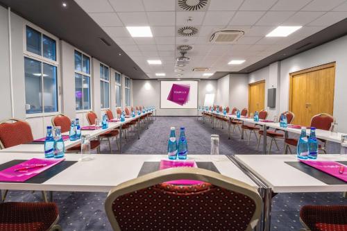a conference room with tables and chairs and a screen at FourSide Hotel Salzburg Messe, Trademark Collection by Wyndham in Salzburg