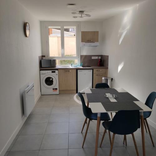 une cuisine avec une table et des chaises ainsi qu'une cuisine avec une cuisinière dans l'établissement Appartement Cosy avec place de parking privée, au Mans