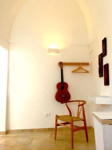 a guitar hanging on a wall next to a chair at Casa Libertà Spacious white scandidesign in Ostuni