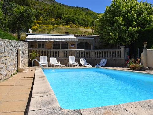 une piscine avec des chaises blanches et une maison dans l'établissement Les Grands Prés des Baronnies, à La Roche-sur-le-Buis