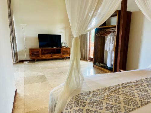a bedroom with a bed with a dresser and a tv at Gayatri in Ubud