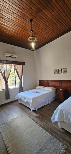 a bedroom with two beds and a wooden ceiling at Leeu Gamka Hotel in Leeu-Gamka