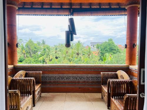 a room with two chairs and a large window at Gayatri in Ubud
