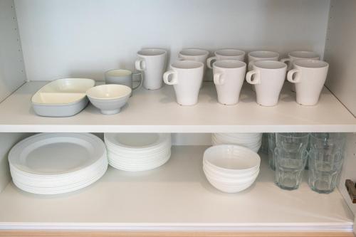 a shelf filled with white cups and plates and bowls at ライトハウス旭川 in Asahikawa