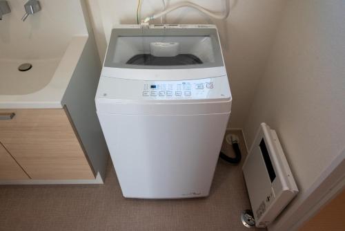 a washing machine in the corner of a bathroom at ライトハウス旭川 in Asahikawa