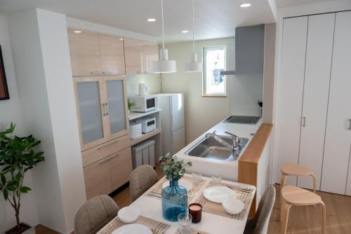 a kitchen with a table with chairs and a sink at ライトハウス旭川 in Asahikawa