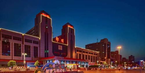 a large building with two towers in a city at night at 欢桔酒店 郑州二七广场丹尼斯大卫城店 in Zhengzhou