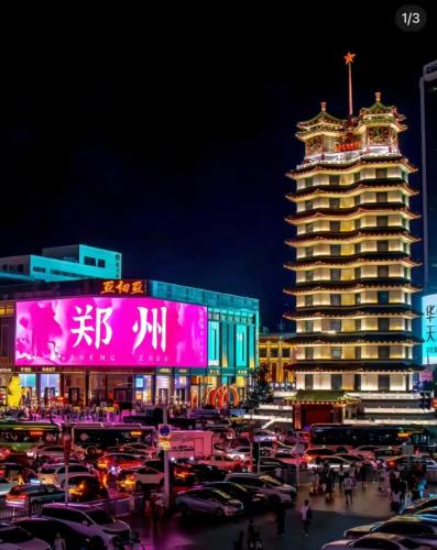 a city with cars parked in a parking lot at night at 欢桔酒店 郑州二七广场丹尼斯大卫城店 in Zhengzhou